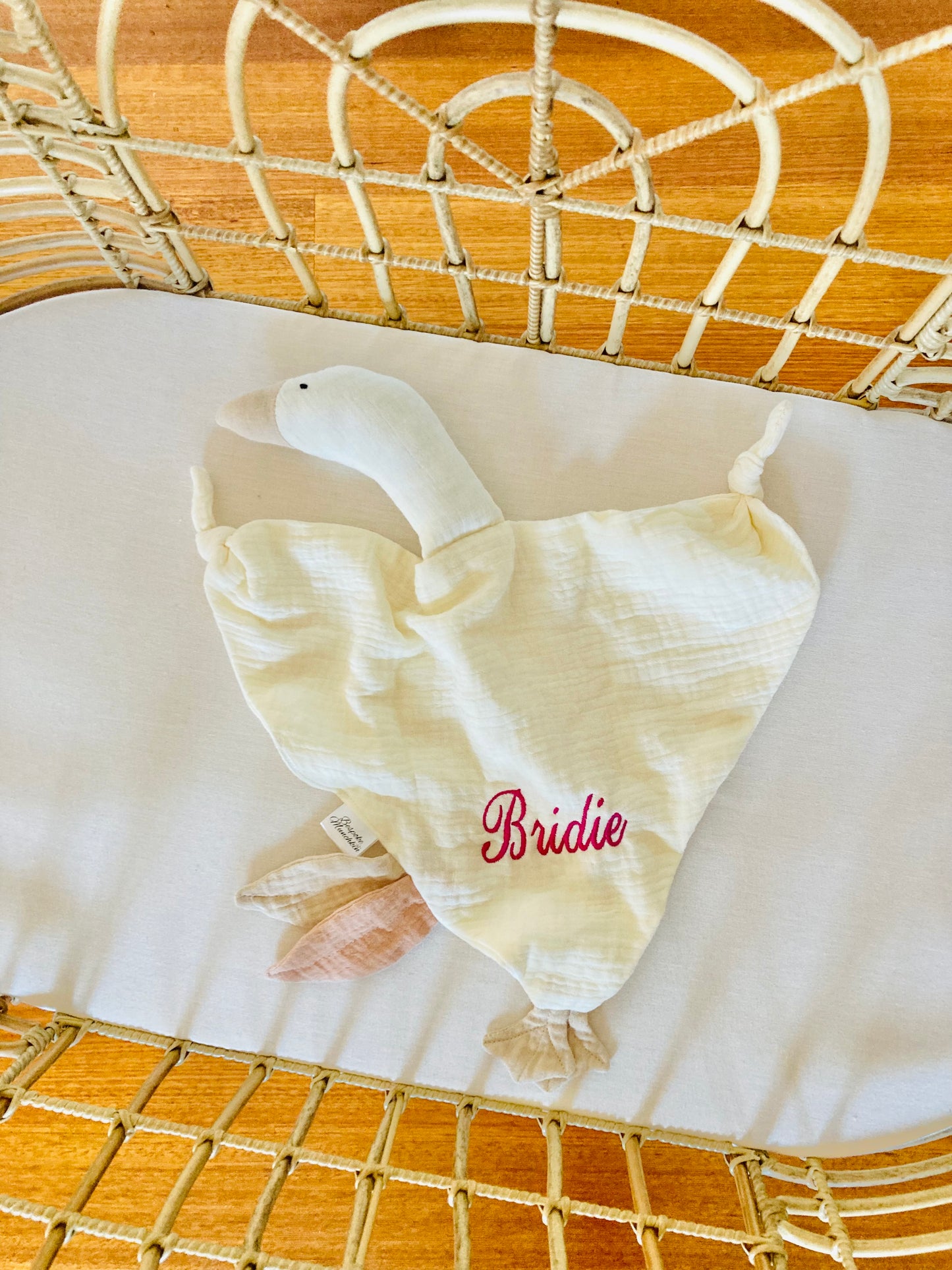 Bird baby comforter with 'Bridie' embroidered on it, placed in a cot.