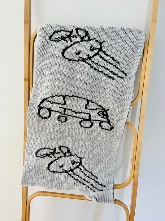 Black and white knitted scarf draped over a rack showing repeated sections of kid drawing. 
